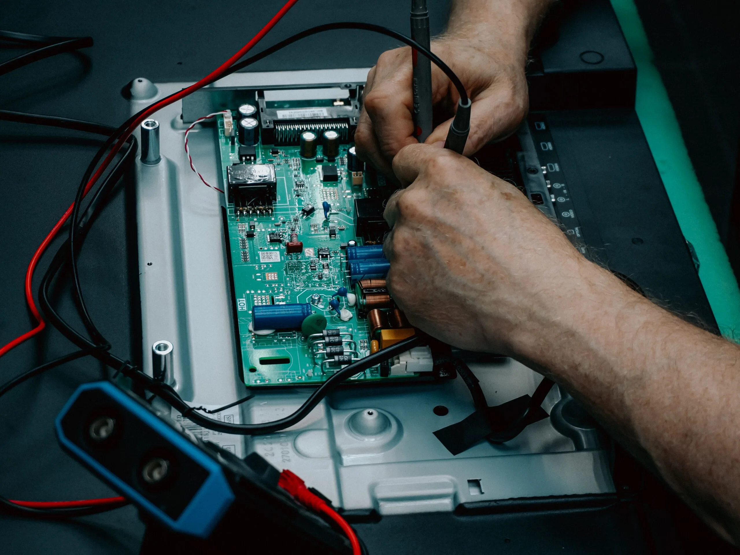 Close-up of hands repairing electronic circuit board, showcasing detailed technology work.